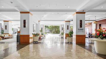 A spacious lobby with a polished floor, wooden accents, and potted plants.