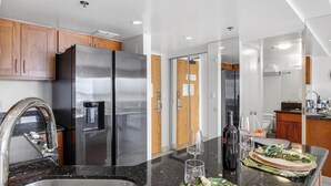 A modern kitchen with stainless steel appliances, a granite countertop, and wooden cabinets. - Suite, Ocean View, Studio (Honolulu)