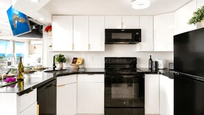 A modern kitchen with white cabinets, a black oven, a microwave, and a refrigerator. - Suite, Ocean View, Studio (Honolulu)