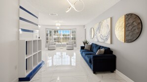 Un interior moderno con un sofá azul, estanterías blancas y arte abstracto en las paredes.