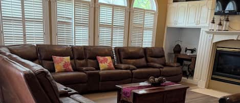 A living room with a sectional sofa, a coffee table, and a fireplace.