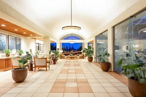 Eine geräumige Lobby mit hoher Decke, großen Fenstern und einer zentralen Sitzecke.