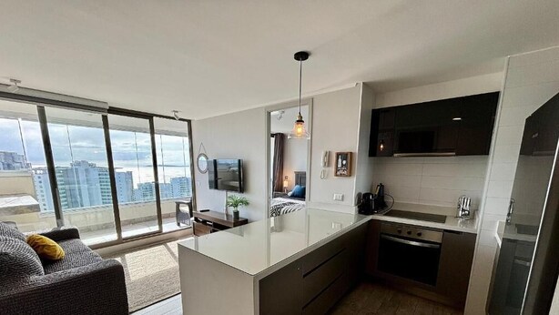 Una cocina moderna con una isla grande, un comedor con sofá y vistas a la ciudad.