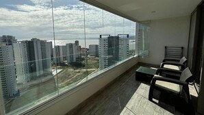 Un apartamento alto con un amplio ventanal, balcón y zona de estar.
