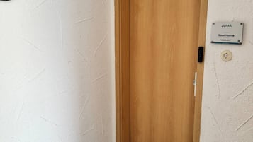 A wooden door with a doormat, a wall-mounted sign, and a textured wall.