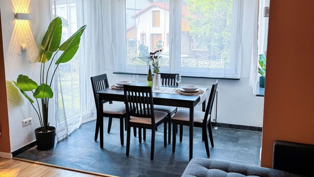A dining area with a table, chairs, and a potted plant.