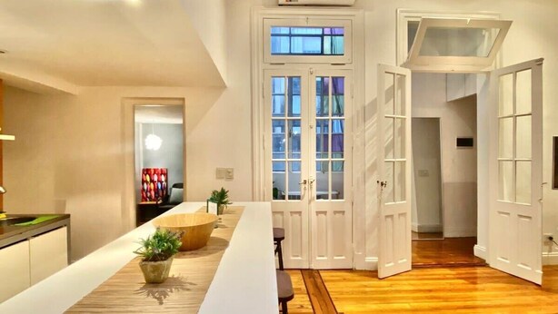 Una cocina moderna con una isla grande, piso de madera y vistas al área de estar.