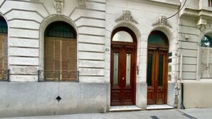 Fachada de edificio con tres ventanales de arco y una puerta central de madera.
