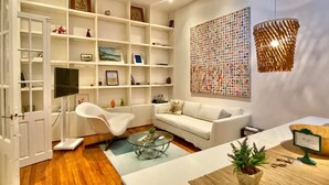 Una sala moderna con un sofá blanco, una mesa de centro de vidrio y un mueble blanco para el televisor.