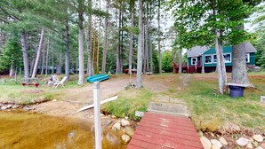 A cabin with a deck, a small stream, and a forested area. - Pioneer Paradise - Lakefront home (Conover)
