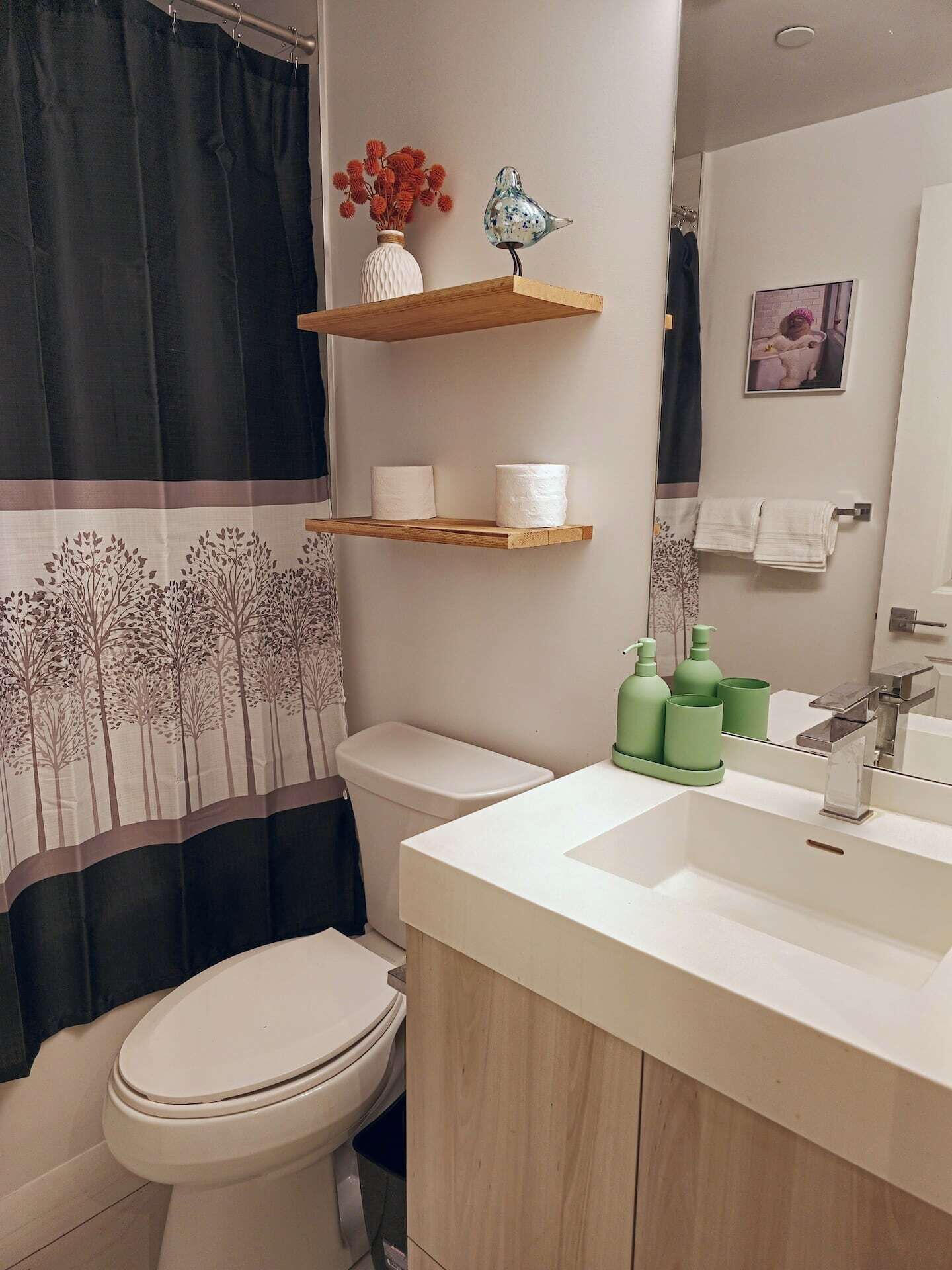 Un bagno con il water, un lavandino, uno specchio e una tenda da doccia.