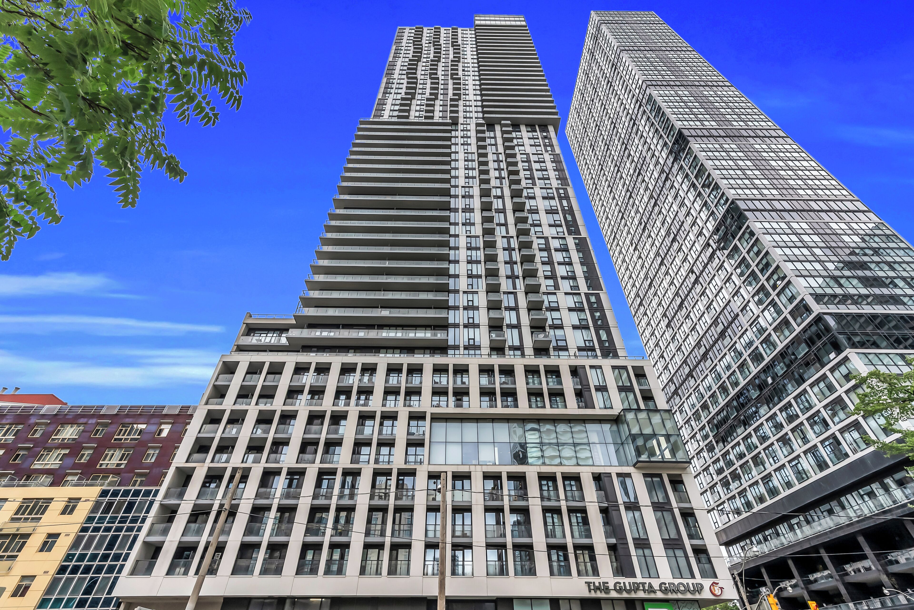 Un immeuble moderne de grande hauteur, doté de nombreux étages, de grandes fenêtres et d’une enseigne bien visible indiquant « The Gupta Group ».