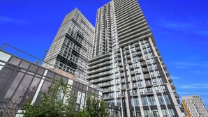 Un edificio moderno de gran altura con varios pisos y balcones, rodeado de otros edificios contemporáneos.