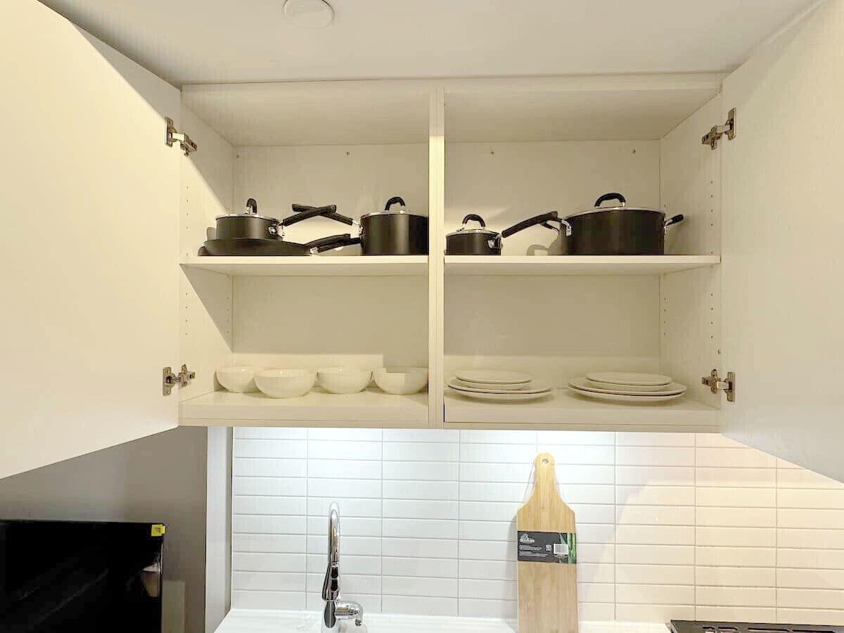 Een keuken met witte kasten, een spoelbak en een houten snijplank aan de muur.