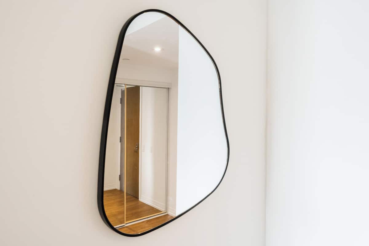 A mirror with a black frame on a white wall.