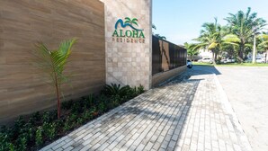 Ein Gebäude mit einem Schild, auf dem 'ALOHA RESIDENCE' steht, und einem gepflasterten Weg.