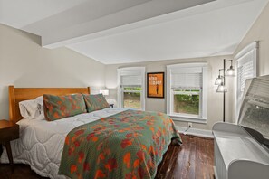 A bedroom with a bed, a nightstand, a window with blinds, and a wall-mounted lamp. - River House in Fennville (Fennville)