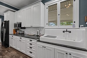A kitchen with white cabinets, a black refrigerator, a microwave, a toaster, and a sink. - River House in Fennville (Fennville)