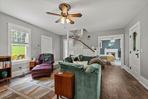 A spacious living room with a fireplace, a ceiling fan, and a view of the outdoors through a window. - River House in Fennville (Fennville)