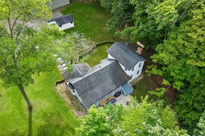 A two-story house with a sloped roof, surrounded by lush greenery and a small pond. - River House in Fennville (Fennville)
