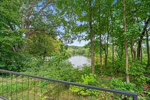 A river surrounded by dense greenery and trees, viewed from a fenced area. - River House in Fennville (Fennville)