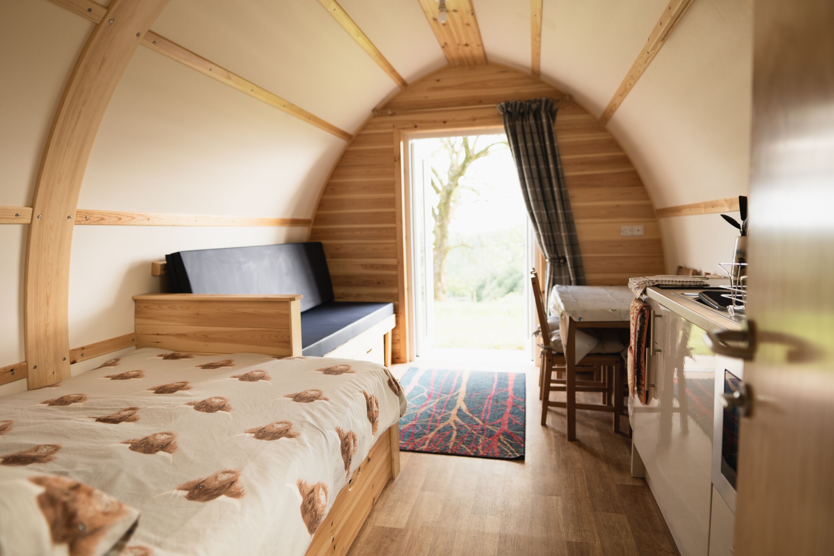 Une pièce confortable et compacte, comprenant un lit, un petit coin salon, une kitchenette et une grande fenêtre.