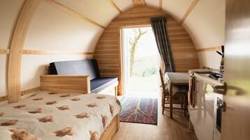 Une pièce confortable et compacte, comprenant un lit, un petit coin salon, une kitchenette et une grande fenêtre.