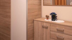 Un mueble de madera con cajones, un espejo encima y un jarrón con flores sobre la encimera.