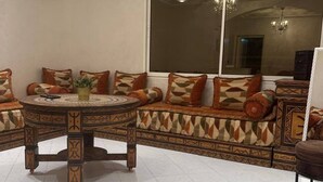 Un salón con una mesa de centro redonda, sofá estampado y un ventanal grande.