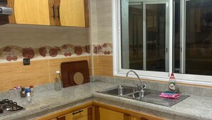 Una cocina con armarios de madera, encimera de granito, pileta de acero inoxidable y ventana con vistas.