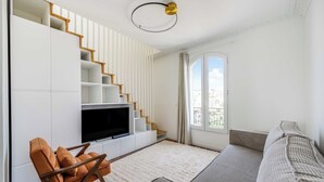 A modern living room with a flat-screen TV, a sofa, a chair, and a staircase. - Charming Duplex 2br/6p - Aubervilliers (Aubervilliers)