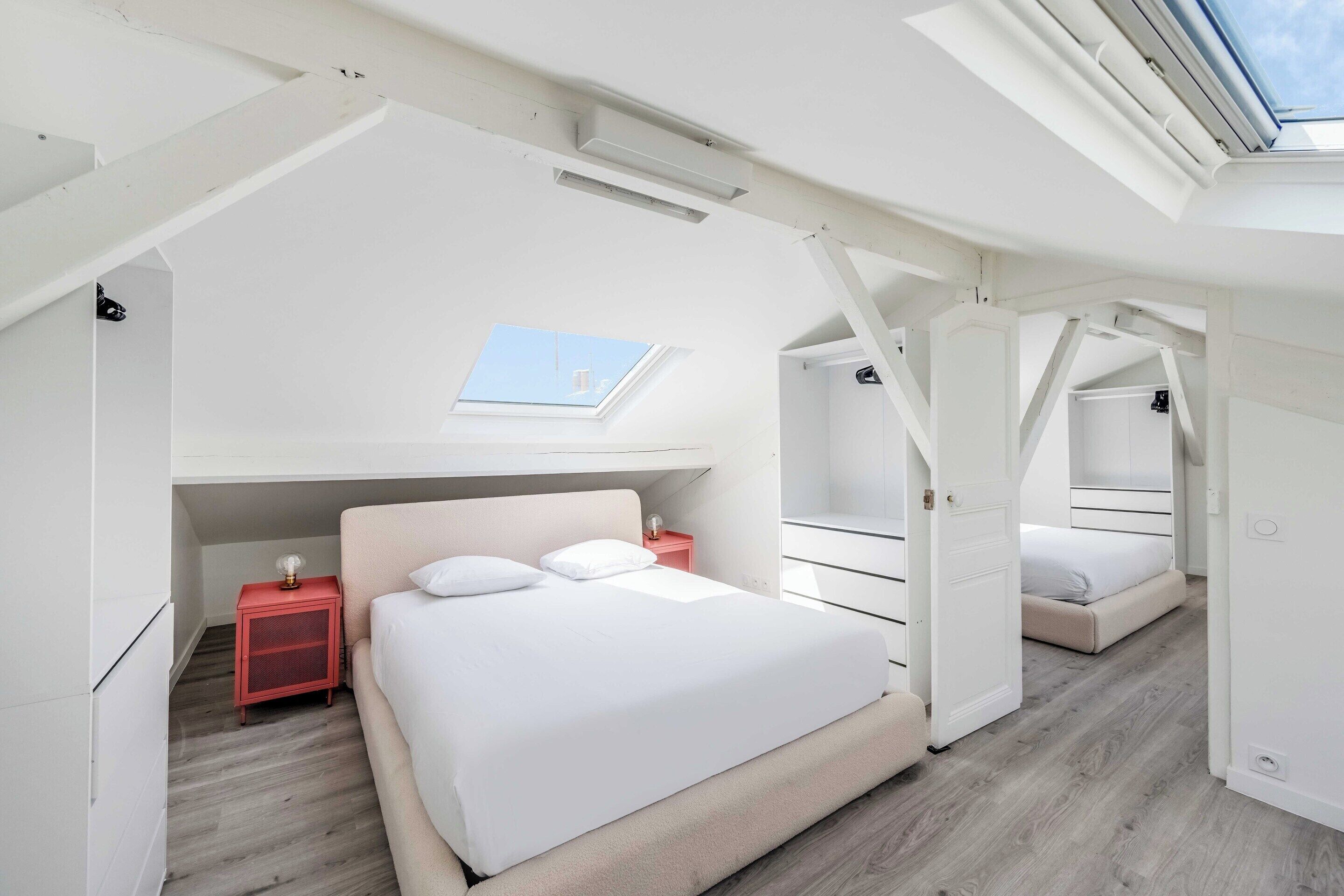 A modern bedroom with a skylight, a bed, a nightstand, and a wardrobe.