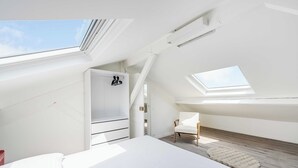 A modern, white room with a skylight, a bed, a chair, and a small rug. - Charming Duplex 2br/6p - Aubervilliers (Aubervilliers)
