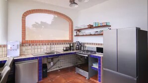 A compact kitchen with a gas stove, a refrigerator, a water dispenser, and a sink. - Casa Moonbeam (Yelapa)