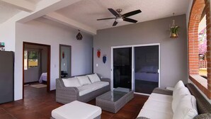 A spacious living area with a sofa, ottoman, and a ceiling fan. - Casa Moonbeam (Yelapa)