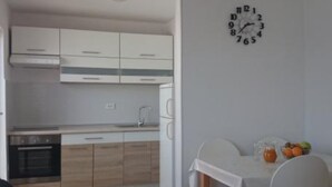 Eine moderne Küche mit Holzausstattung, einem eingebauten Backofen und einem Essbereich mit weißem Tisch und Stühlen.