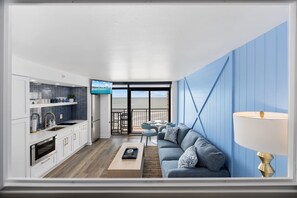 Ein modernes Wohnzimmer mit Sofa, Fernseher und einem Balkon mit Blick.