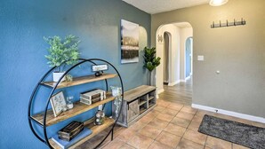 A hallway with a blue wall, a wooden bench, a round metal shelf with books, a small plant, and a door with a light fixture. - Spacious, Cozy 3 Bedroom 2 bath North End Home (Tacoma)