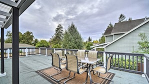 An outdoor patio with a table and chairs, a covered area, and a view of a house and trees. - Spacious, Cozy 3 Bedroom 2 bath North End Home (Tacoma)
