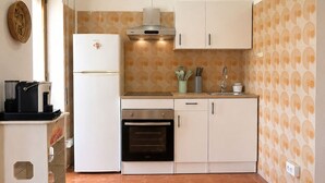 Cuina compacta amb nevera, forn i cafetera.