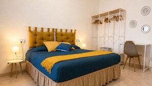 Un dormitori amb un llit, taules de nit, un escriptori i un armari.