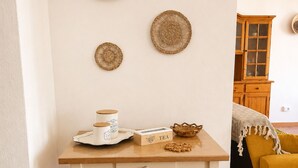 Una habitació amb una taula blanca, un butaquito groc i tres decoracions murals teixides.