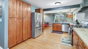 Cocina moderna con armarios de madera, electrodomésticos de acero inoxidable y una isla central.