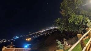 A nighttime view of a coastal area with a paved walkway, a wooden fence, and a tree. - Philomelion Lodge (Aksehir)