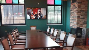 A conference room with a long table and chairs, a television screen, and a brick fireplace. - Philomelion Lodge (Aksehir)