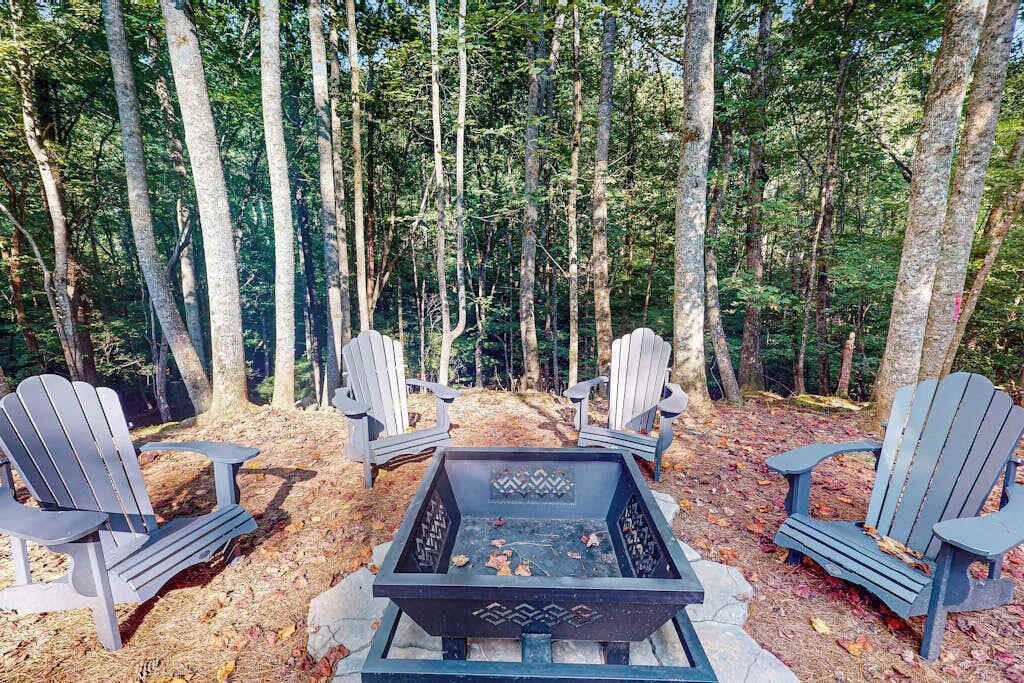 Entorno boscoso con sillas Adirondack y una fosa para el fuego.