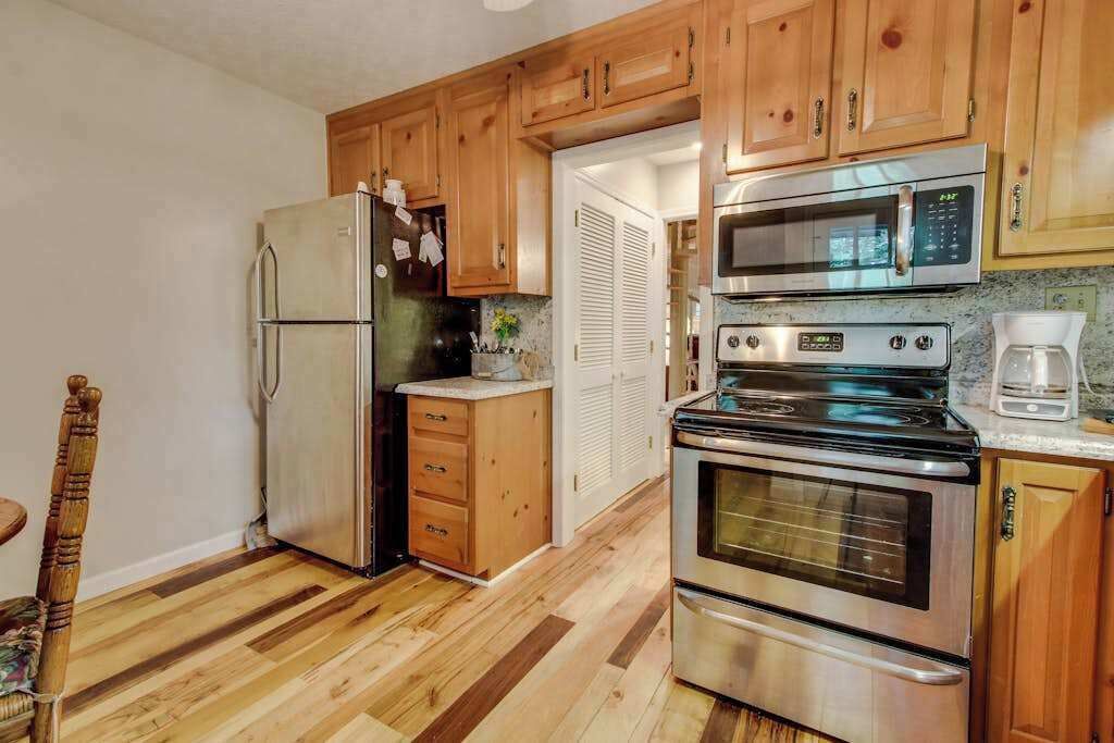 A kitchen with wooden cabinets, a stainless steel refrigerator, a microwave, an oven, and a coffee maker.