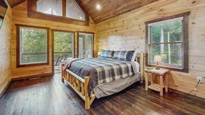 Un dormitorio de cabaña de madera con cama, mesita de noche y ventana.