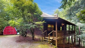 Eine rustikale Holzhütte mit einer Holzterrasse und einer Treppe, die zu einer Veranda führt.