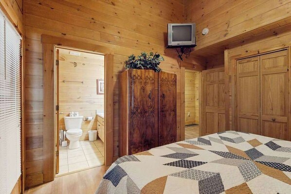L’intérieur d’un chalet en bois comprend un lit, un téléviseur, une armoire et une salle de bain.